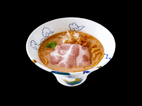 RAIJIN's Gyokai Tonkotsu Shoyu Frozen Ramen with pork slices in an ornate bowl on black background