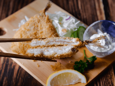 Aji Fry 60g - Breaded horse mackerel paired with lemon wedge, coleslaw, and dipping sauce on a wooden board